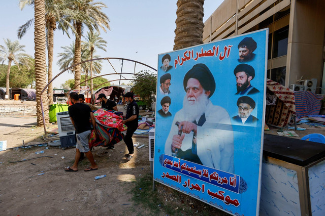 Pengikut pemimpin Syiah Irak Muqtada al-Sadr membawa barang-barang mereka saat mereka mundur dari jalan-jalan setelah bentrokan keras, di Zona Hijau di Baghdad, Irak, Selasa (30/8/2022). Foto: Ahmad Saad/REUTERS