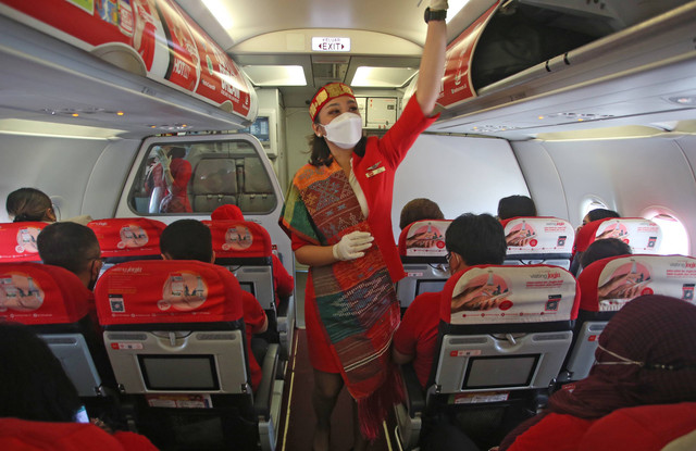 Kru pesawat dengan mengenakan kain ulos dan sortali atau ikat kepala merapikan kompartemen sebelum melakukan penerbangan ke Silangit, Tapanuli Utara di Terminal 1 A Bandara Soekarno Hatta, Tangerang, Banten, Jumat (2/9/2022). Foto: Muhammad Iqbal/Antara Foto