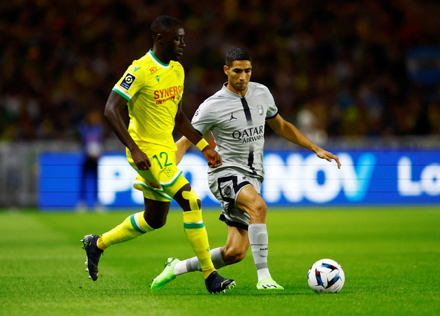 Achraf Hakimi dari Paris St Germain duel dengan Dennis Appiah dari Nantes saat pertandingan di Stade de la Beaujoire, Louis Fonteneau, Nantes, Prancis, Sabtu (3/9/2022). Foto: Stephane Mahe/Reuters