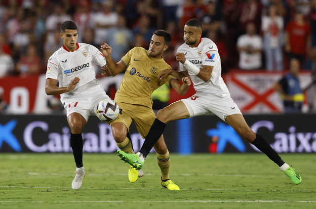 Erik Lamela dari Sevilla dan Youssef En-Nesyri duel dengan Andreas Christensen dari FC Barcelona saat pertandingan di Ramon Sanchez Pizjuan, Seville, Spanyol, Sabtu (3/9/2022). Foto: Marcelo Del Pozo/Reuters