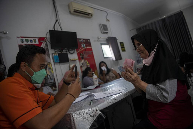 Petugas PT Pos Indonesia (Persero) memotret penerima bantuan langsung tunai (BLT) pengalihan subsidi BBM tahap pertama di Gambir, Jakarta Pusat, Jumat (2/9/2022). Foto: Sigid Kurniawan/Antara Foto