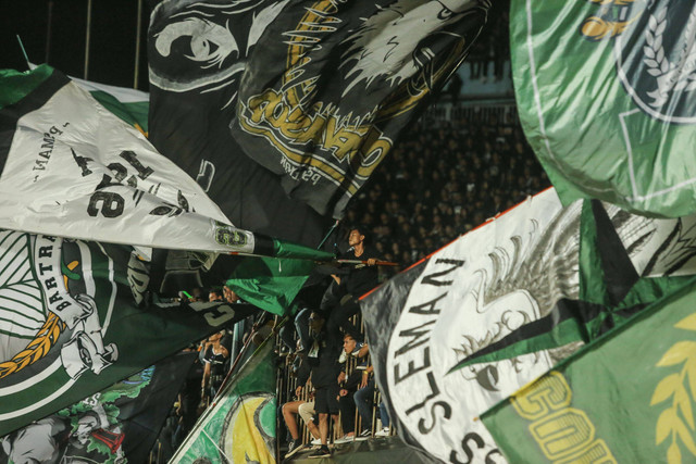 Pendukung PSS Sleman mengibarkan bendera saat pertandingan Liga 1 PSS Sleman melawan Persib Bandung di Stadion Maguwoharjo, Sleman, DI Yogyakarta, Jumat (19/8/2022).  Foto: Hendra Nurdiyansyah/ANTARA FOTO