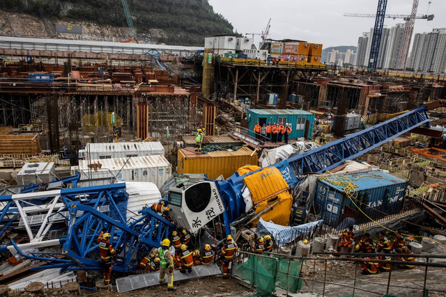 Anggota tim Urban Search And Rescue (USAR) (C) bekerja dengan derek di lokasi konstruksi yang runtuh, Hong Kong, Rabu (7/9/2022). Foto: Isaac Lawrence/AFP