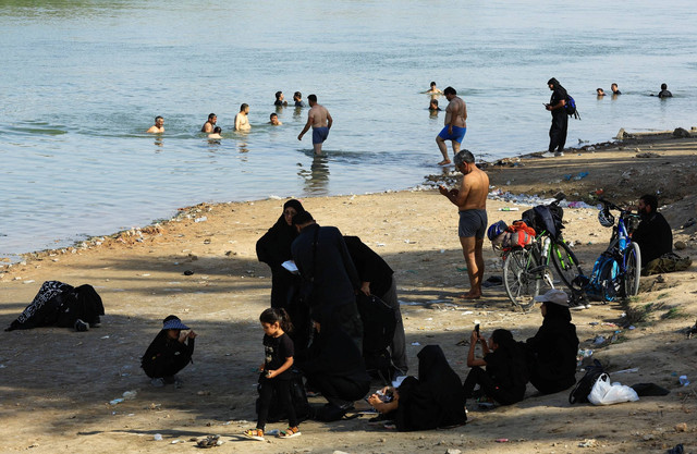 Peziarah Muslim Syiah mendinginkan diri di sungai Efrat, saat dalam perjalanan menuju Kerbala di Najaf, Irak, Rabu (14/9/2022). Foto: Thaier Al-Sudani/Reuters