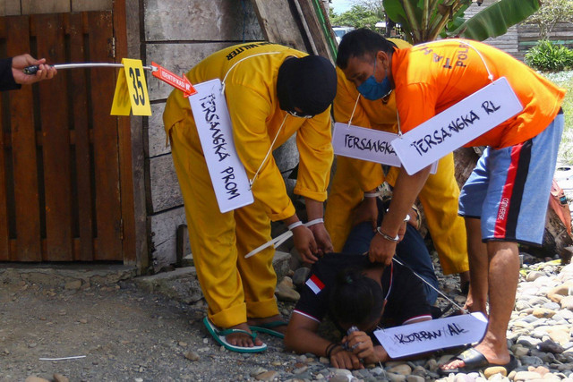 Tiga tersangka melakukan adegan saat mengikuti rekonstruksi pembunuhan dan mutilasi empat warga di Timika, Papua, Sabtu (3/9/2022).  Foto: Sevianto Pakiding/ANTARA FOTO