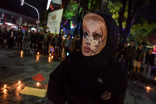 Mahasiswa yang tergabung gerakan Tasik Kelabu mengenakan topeng hacker Bjorka saat menggelar aksi teaterikal di Taman Kota Tasikmalaya, Jawa Barat, Rabu (21/9) malam. Foto: Adeng Bustomi/Antara Foto