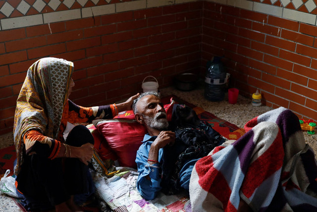 Seorang wanita pengungsi Rehmat Khatoon merawat suaminya yang sakit Mehdi Hassan (65) saat mengungsi di sebuah sekolah di Karachi, Pakistan, Kamis (22/9/2022). Foto: Akhtar Soomro/Reuters