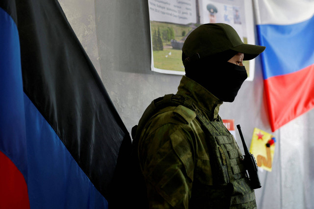 Seorang anggota layanan Republik Rakyat Donetsk yang memproklamirkan diriberjaga di pintu tempat pemungutan suara menjelang referendum yang direncanakan tentang bergabungnya Republik Rakyat Donetsk ke Rusia, di Donetsk, Ukraina. Foto: Alexander Ermochenko/REUTERS