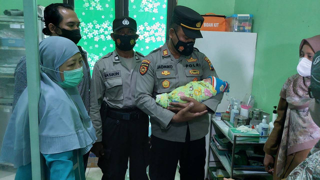Kapolsek Dander, Polres Bojonegoro AKP Jadmiko SH, saat menggendong bayi yang ditemukan warga di Desa Sumberarum, Kecamatan Dander, Kabupaten Bojonegoro. (foto: dok istimewa)