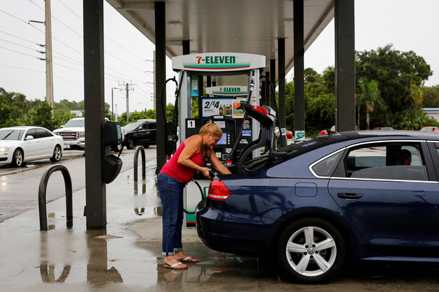 Seorang wanita mengisi sebuah wadah dengan bensin di sebuah pompa bensin, saat Badai Ian berputar menuju negara bagian, di Port Charlotte, Florida, AS, Selasa (27/9/2022). Foto: Marco Bello/REUTERS