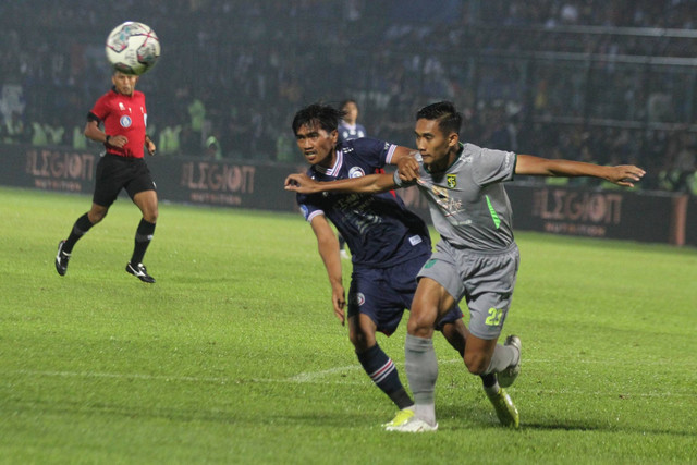 Pesepak bola Arema FC Jayus Hariono (kiri) dan pesepak bola Persebaya Surabaya Rizki Ridho (kanan) beradu cepat untuk menjangkau bola dalam pertandingan lanjutan BRI Liga 1 di Stadion Kanjuruhan, Malang, Jawa Timur, Sabtu (1/10/2022). Foto: Ari Bowo Sucipto/ANTARA FOTO
