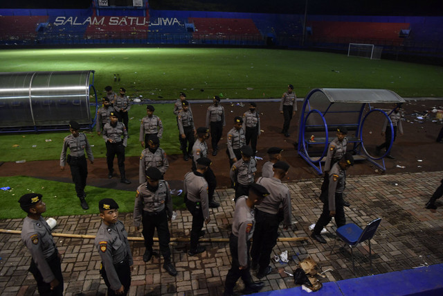 Sejumlah polisi melintas di pinggir lapangan Stadion Kanjuruhan, Malang, Jawa Timur, Minggu (2/10/2022). Foto: Zabur Karuru/Antara Foto