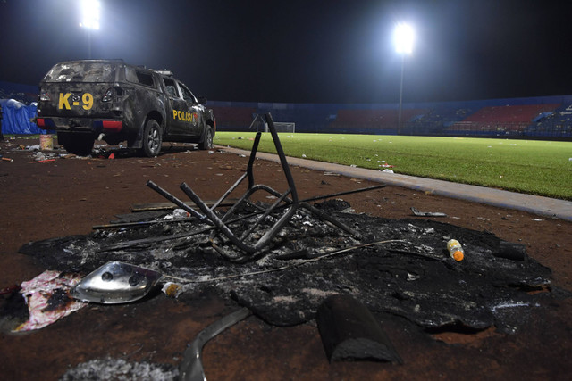 Sebuah mobil polisi berada di pinggir lapangan pascakerusuhan di Stadion Kanjuruhan, Malang, Jawa Timur, Minggu (2/10/2022). Foto: Zabur Karuru/Antara Foto