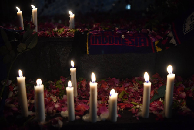 Sejumlah lilin dinyalakan di depan Patung Singa Stadion Kanjuruhan, Malang, jawa Timur, Minggu (2/10/2022). Foto: Zabur Karuru/Antara Foto
