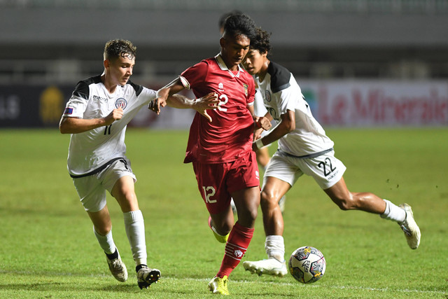 Pesepak bola Tim Nasional U-17 Indonesia Muhammad Narendra Tegar (tengah) berusaha melewati hadangan pesepak bola Tim Nasional U-17 Guam Levi Berg (kiri) dalam laga Grup B Kualifikasi Piala Asia U-17 2023 di Stadion Pakansari. Foto: Aditya Pradana Putra/ANTARA FOTO