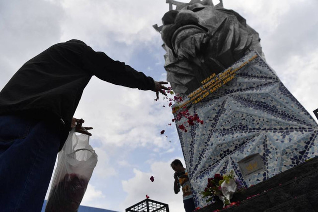 Suporter Arema FC (Aremania) menabur bunga di Patung Singa Stadion Kanjuruhan, Malang, jawa Timur, Minggu (2/10/2022). Foto: Zabur Karuru/ANTARA FOTO