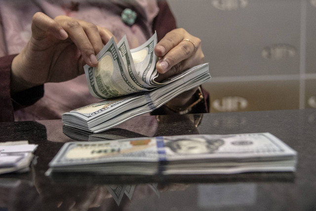 Petugas menghitung uang pecahan dolar AS di gerai penukaran mata uang asing VIP (Valuta Inti Prima) Money Changer, Jakarta, Selasa (4/10/2022). Foto: Muhammad Adimaja/Antara Foto