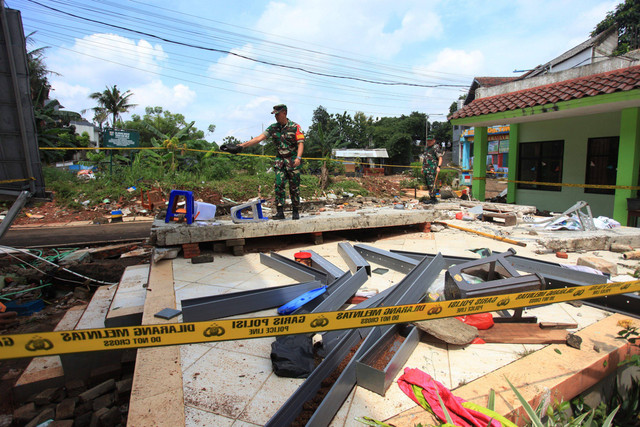 Prajurit TNI mengamati tembok roboh akibat banjir di MTSN 19 Pondok Labu, Jakarta,  Jumat (7/10/2022).  Foto: Reno Esnir/ANTARA FOTO