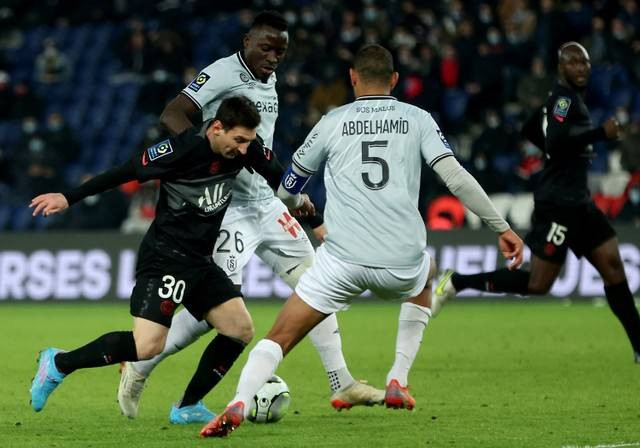 Pemain Paris Saint-Germain (PSG) Lionel Messi berusaha melewati pemain Reims pada pertandingan lanjutan Liga Prancis di stadion Parc des Princes, Paris, Prancis, Senin (24/1/2022). Foto: Thomas SAMSON / AFP