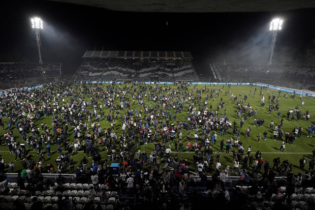 Supoeter  yang terkena gas air mata menyerbu lapangan setelah pertandingan Gimnasia y Esgrima La Plata melawan Boca Juniors  dihentikan karena bentrokan antara pendukung dan polisi di luar stadion Juan Carmelo Zerillo, di La Plata, Argentina. Foto: Jose Brusco/REUTERS