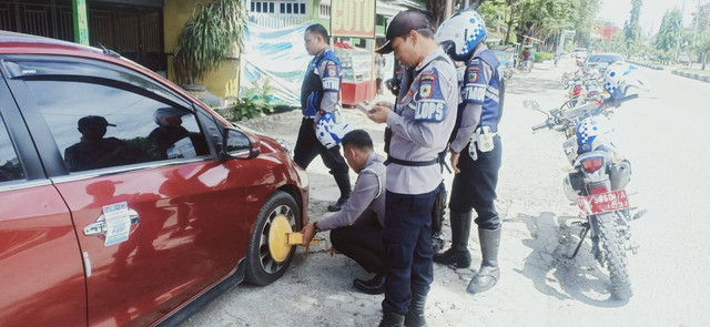 Dishub Kota Palu saat menggembok salah satu mobil yang kedapatan parkir di trotoar. Foto: Tim PaluPoso