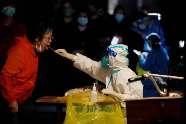 Seorang pekerja medis dengan APD mengumpulkan swab dari seorang warga untuk pengujian COVID-19, di Shanghai, China, Kamis (13/10/2022). Foto: Aly Song/REUTERS