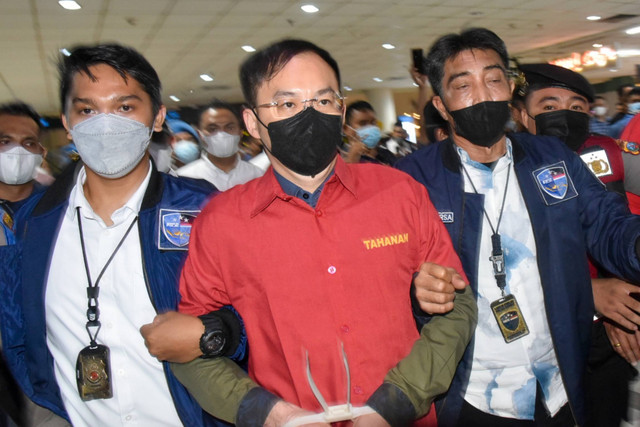 Polisi membawa tersangka bandar judi online Apin BK (tengah) saat tiba di Bandara Kualanamu, Deli Serdang, Sumatera Utara, Senin (17/10/2022). Foto: Fransisco Carolio/ANTARA FOTO