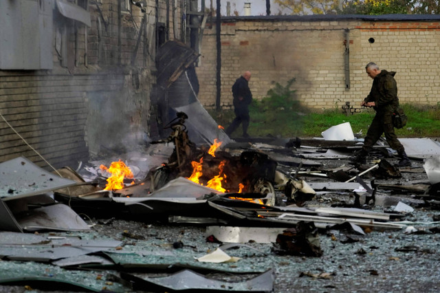 Petugas di lokasi ledakan bom mobil di luar gedung stasiun TV lokal di kota Melitopol di Ukraina Selasa (25/10). Foto: STR/AFP
