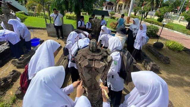 Membersihkan nisan kuno sambil belajar pelestarian budaya. Foto: Disbudpar