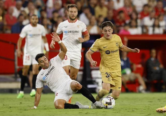 Marcos Acuna dari Sevilla duel dengan Gavi pemain FC Barcelona saat pertandingan di Ramon Sanchez Pizjuan, Seville, Spanyol, Sabtu (3/9/2022). Foto: Marcelo Del Pozo/Reuters