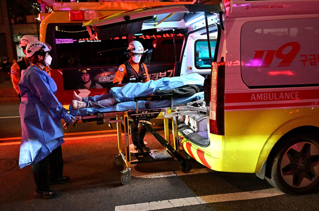 Jenazah korban serangan jantung diangkut ke dalam ambulans, usai tragedi festival Halloween di kawasan hiburan malam populer Itaewon di Seoul, Korea Selatan, Minggu (30/10/2022). Foto: Jung Yeon-je/AFP