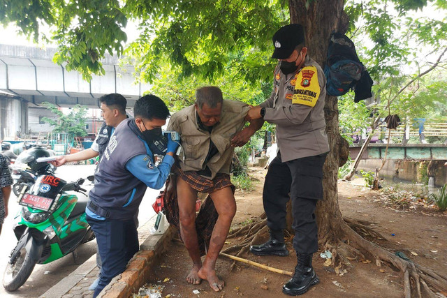 Anggota Bhabinkamtibmas kelurahan Roa Malaka Polsek Tambora, Aiptu Cecep Supriadi yang membantu seorang tunawisma di Jalan perniagaan barat pasar pagi Tambora Jakarta Barat, Jumat (4/11/2022).  Foto: Dok. Polsek Tambora