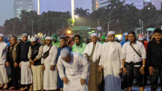 Massa aksi 411 menunaikan ibadah Salat Magrib di tengah hujan deras, Jumat (4/11/2022). Foto: Jonathan Devin/kumparan