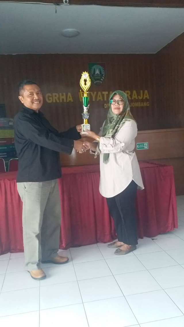 Ibu Ismiati selaku lurah desa Sumberjo berpose dengan piala lomba (dokumentasi pribadi)