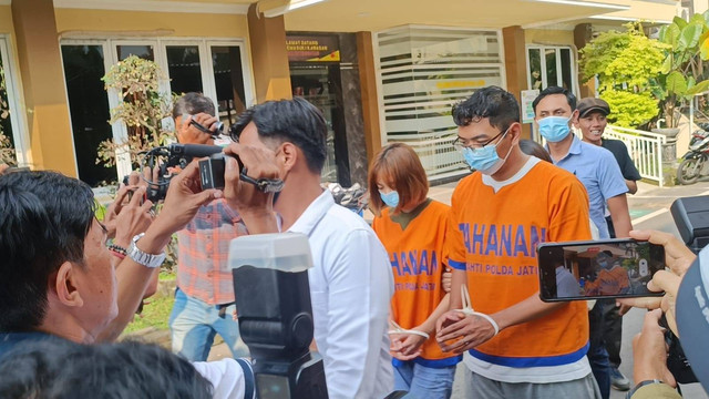 Dua tersangka pemeran video porno kebaya merah mengenakan baju tahanan di Mapolda Jatim, Selasa (8/11/2022). Foto: Farusma Okta Verdian/kumparan