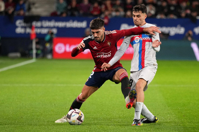 Pemain FC Bacelona Pedri berebut bola dengan pemain Osasuna pada pertandingan lanjutan Liga Spanyol di stadion El Sadar, Pamplona, Spanyol.  Foto: Cesar Manso/AFP