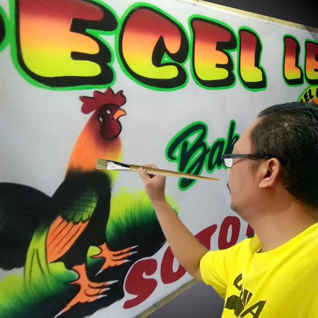 Proses pembuatan spanduk pecel lele lukis oleh pengrajin, Hartono. Foto: Dok. Hartono