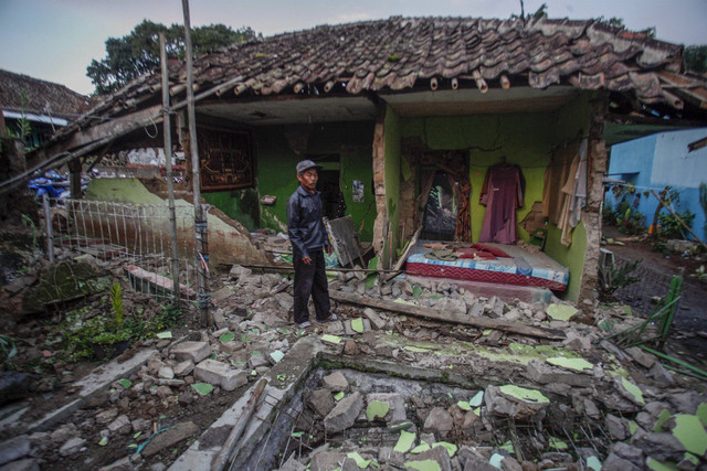 Warga berdiri di depan rumahnya yang rusak akibat gempa di Desa Cibeureum, Kabupaten Cianjur, Jawa Barat, Senin (21/11/2022).  Foto: Yulius Satria Wijaya/ANTARA FOTO