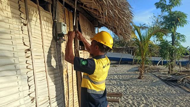 Petugas PLN memasang meteran listrik baru di rumah warga kurang mampu.