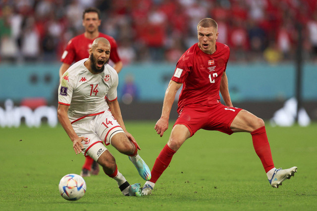 Pemain Timnas Denmark Rasmus Kristensen berebut bola dengan pemain Timnas Tunisia Aissa Laidouni pada pertandingan Grup D Piala Dunia 2022 Qatar di Education City Stadium, Al Rayyan, Qatar. Foto: Matthew Childs/REUTERS