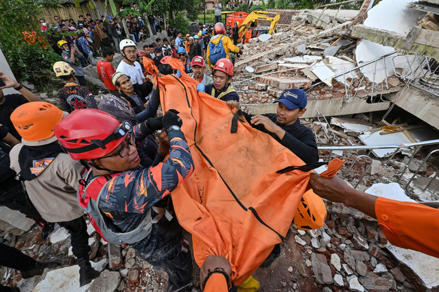 Petugas penyelamat membawa jenazah korban gempa di Cianjur, Jawa Barat, Selasa (22/11/2022). Foto: Adek Berry/AFP