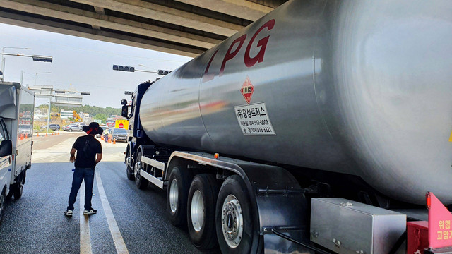 Seorang anggota serikat Solidaritas Pengemudi Truk Kargo berdiri di samping truk LPG di Ulsan, Korea Selatan. Foto: Byungwook Kim/REUTERS