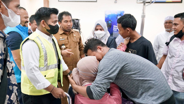 Aida (duduk), TKW asal Aceh Besar yang terkatung-katung dan menderita sakit parah di Malaysia tiba di Aceh melalui Bandara SIM, Senin (28/11) siang. Foto: Humas Aceh Besar