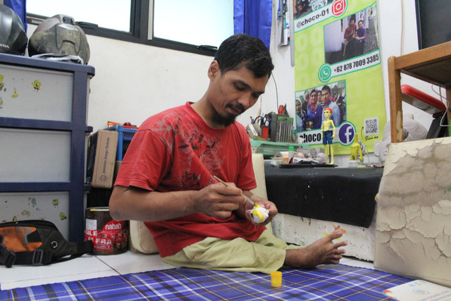 Wawang Sunarya sedang mengecat action figure. Foto: Lutfi Sheykal