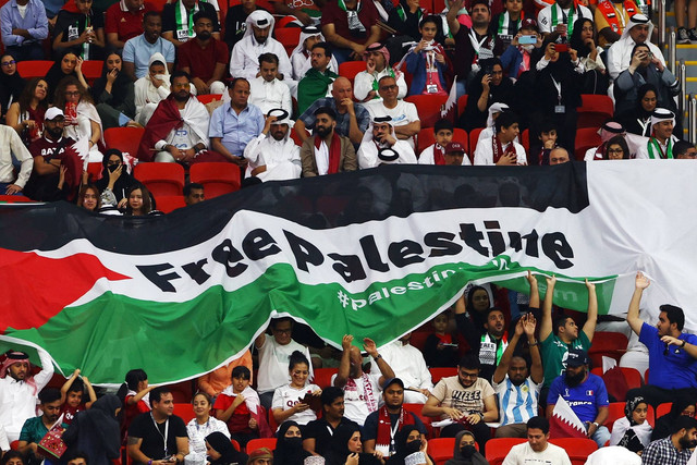 Suporter membentangkan bendera Palestina saat pertandingan Timnas Belanda melawan Qatar pada pertandingan Grup A Piala Dunia 2022 Qatar di Stadion Al Bayt, Al Khor, Qatar. Foto: Bernadett Szabo/REUTERS