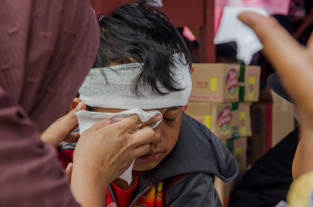 Warga mengusap air mata anak penyintas gempa Cianjur yang mengikuti kegiatan menggambar di posko pengungsian Lapangan Cariu, Cugenang, Cianjur, Jawa Barat, Rabu (30/11/2022). Foto: Novrian Arbi/ANTARA FOTO