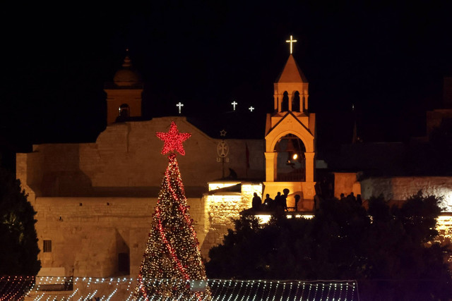 Pohon Natal menyala di Manger Square di luar Gereja Kelahiran, di Bethlehem, di Tepi Barat yang diduduki Israel, Sabtu (3/12/222). Foto: Hazem Bader/AFP