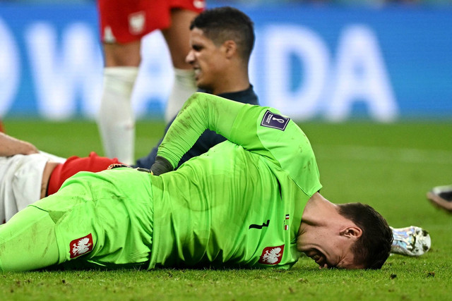 Kiper Polandia Wojciech Szczesny dan pemain Prancis Raphael Varane bereaksi setelah mengalami cedera pada Babak 16 Besar Piala Dunia 2022, di Stadion Al Thumama, Doha, Qatar, Minggu (12/4/2022). Foto: Fabrizio Bensch/REUTERS