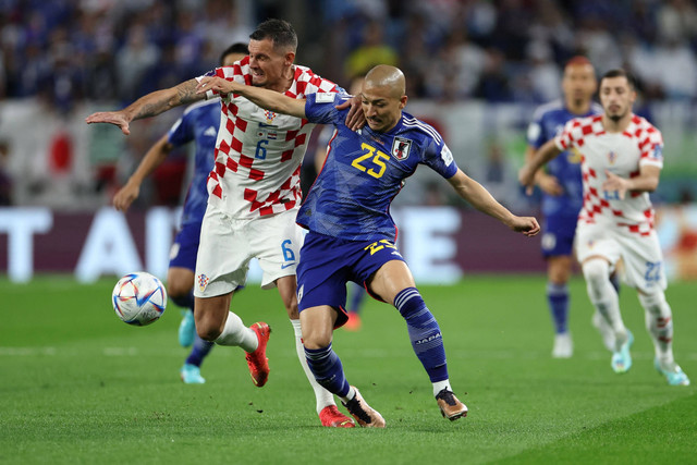 Pemain Timnas Kroasia Dejan Lovren berebut bola dengan pemain Timnas Jepang Daizen Maeda pada pertandingan babak 16 besar Piala Dunia 2022 Qatar di Stadion Al Janoub, Al Wakrah, Qatar. Foto: Marko Djurica/REUTERS
