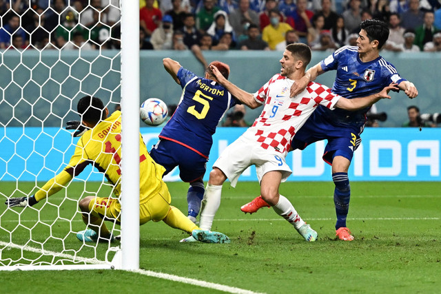 Pemain Timnas Kroasia Andrej Kramaric berebut bola dengan pemain Timnas Jepang Yuto Nagatomo dan Shogo Taniguchi pada pertandingan babak 16 besar Piala Dunia 2022 Qatar di Stadion Al Janoub, Al Wakrah, Qatar. Foto: Marko Djurica/REUTERS